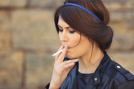 Beautiful young woman smoking weed outdoorsの写真素材
