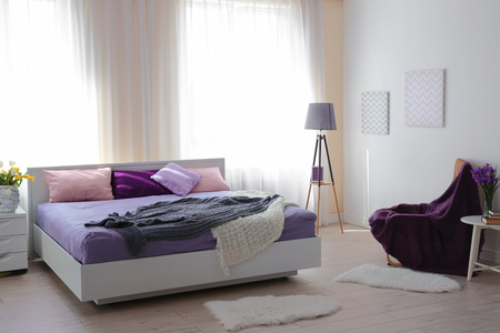 Interior of light modern bedroom with lilac beddingの写真素材