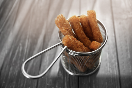 Metal basket with cheese sticks on tableの写真素材