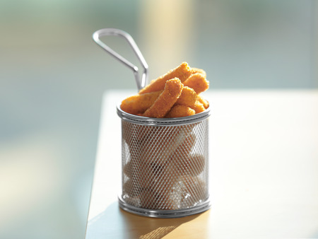 Metal basket with cheese sticks on tableの写真素材