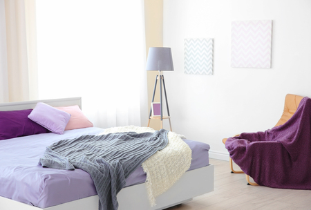Interior of light modern bedroom with lilac beddingの写真素材