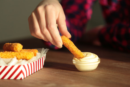 Woman eating cheese sticks with sauce on tableの写真素材