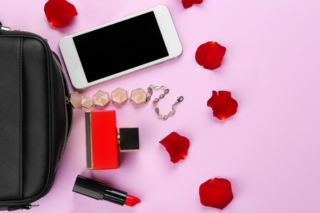 Perfume bottle with cosmetic bag and phone on color backgroundの写真素材