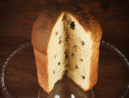 Glass stand with delicious sliced Easter cake and raisins on wooden backgroundの写真素材