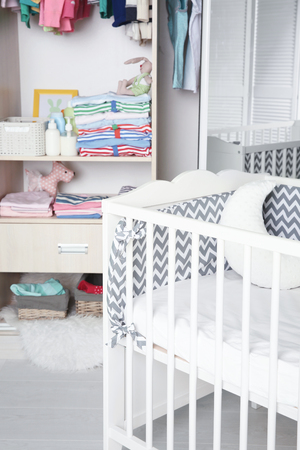 Crib and wardrobe with clothes in light baby roomの写真素材