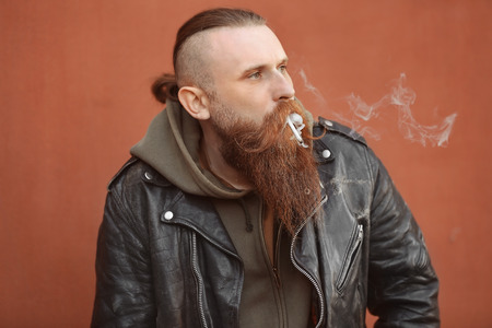 Bearded man smoking weed outdoors on color backgroundの写真素材