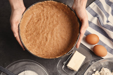 Woman making tasty cheesecake on kitchenの写真素材