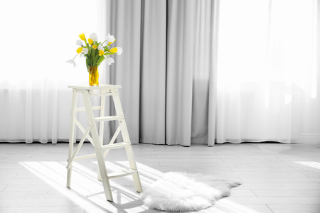 Vase with beautiful white and yellow tulips on wooden step ladderの写真素材