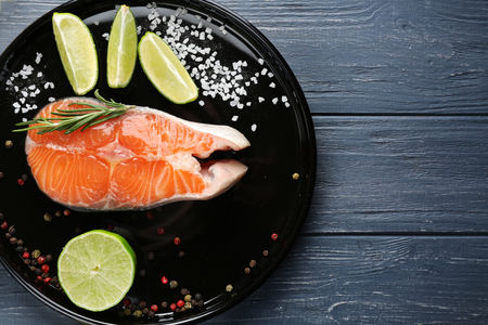 Fresh salmon steak with slices of lime on baking dishの写真素材