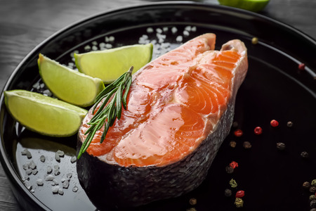 Fresh salmon steak with slices of lime on baking dishの写真素材