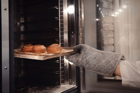 Woman holding tray with buns in bakeryの写真素材