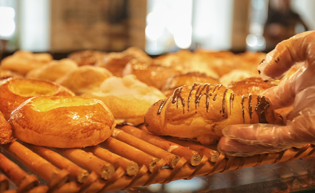 Female hand with pastry at counter in shop
