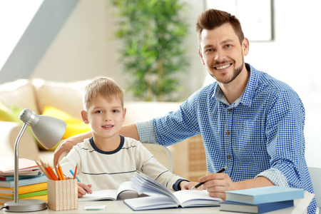 Father and son doing homework together at homeの写真素材