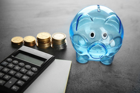Composition of piggy bank, coins and calculator on grey tableの写真素材