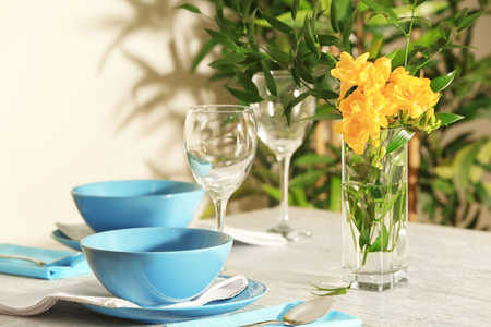 Beautiful festive table setting and vase of flowers in light roomの写真素材