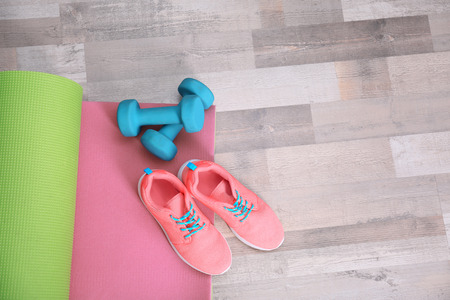 Yoga mat with sneakers and dumbbells on the floor, top viewの写真素材