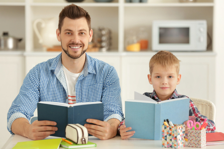 Father and son doing homework together at homeの写真素材