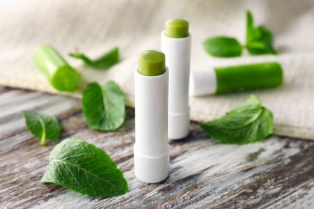 Hygienic lipsticks with lemon balm on wooden tableの写真素材