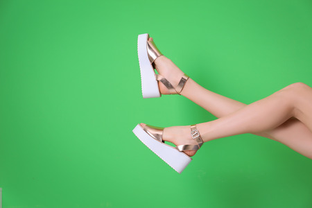 Female legs in stylish shoes on color backgroundの写真素材