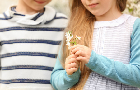 Pretty little girl and cute boy walking in spring park, closeupの写真素材