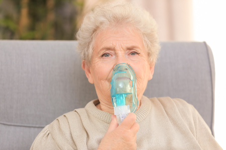 Elderly woman using asthma machine at homeの写真素材
