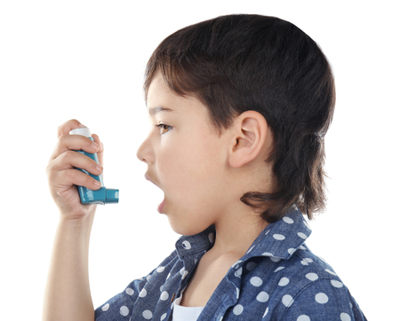 Boy using inhaler during asthmatic attack on white backgroundの写真素材