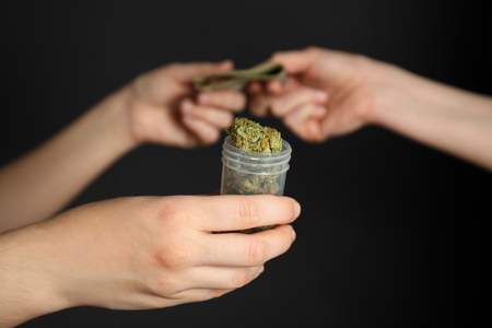 Woman buying weed buds in container on black backgroundの写真素材