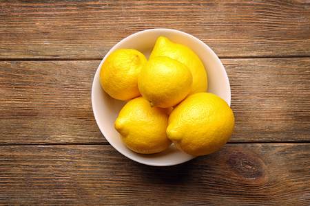 Bowl with delicious lemons on wooden tableの写真素材