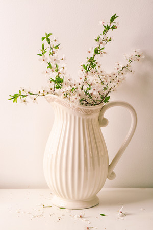 Jug with blossoming spring branches on tableの写真素材