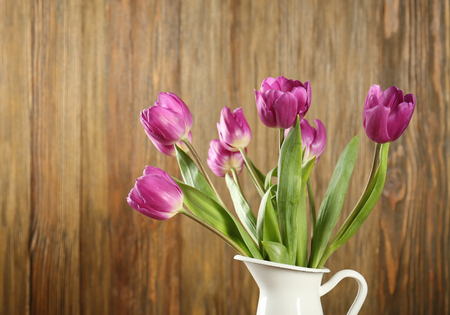 Vase with beautiful bouquet of lilac tulips on wooden backgroundの写真素材
