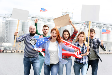 Group of protesting young people with American flag and factory on backgroundの写真素材