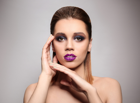Beautiful young woman with creative makeup on color backgroundの写真素材