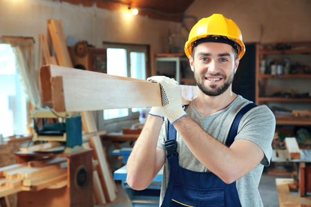 Handsome young carpenter with boards in workshopの写真素材