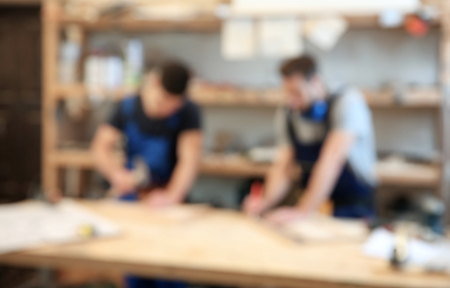 Blurred view of two carpenters in workshopの写真素材