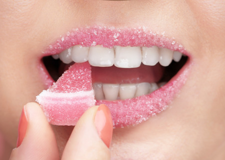 Beautiful young woman with marmalade in mouth, closeupの写真素材