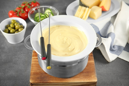 Fondue set, cheese and vegetables on tableの写真素材