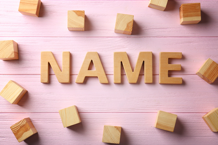Word NAME and wooden cubes on color background. Concept of choosing baby nameの写真素材