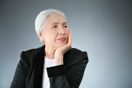 Beautiful elegant elderly woman on gray backgroundの写真素材