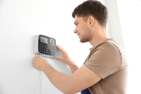 Young electrician installing security alarm on wallの写真素材