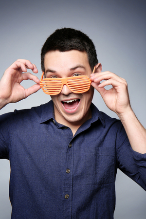 Happy young man with party glasses on gray backgroundの写真素材