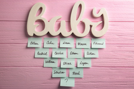 Word BABY and paper stickers with different names on color wooden background. Concept of choosing baby nameの写真素材