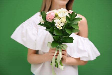 Young woman holding beautiful bouquet with white freesia on color backgroundの写真素材