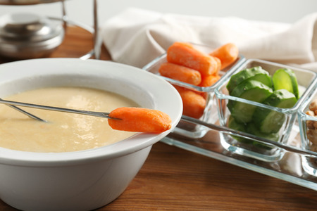 Cheese fondue with carrot on tableの写真素材