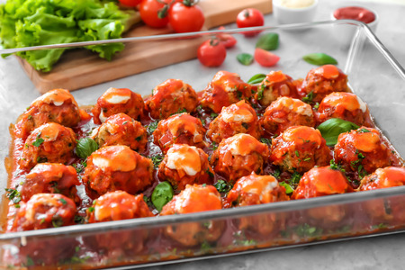 Delicious turkey meatballs in glass casserole dish on light tableの写真素材