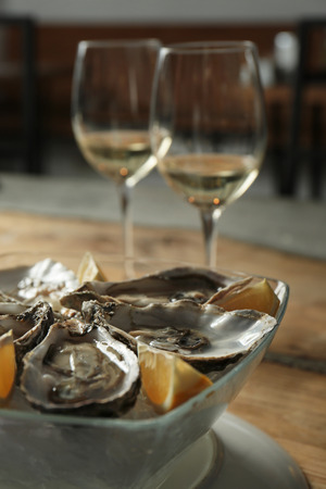 Delicious oysters with slices of lemon on ice cubes in bowlの写真素材