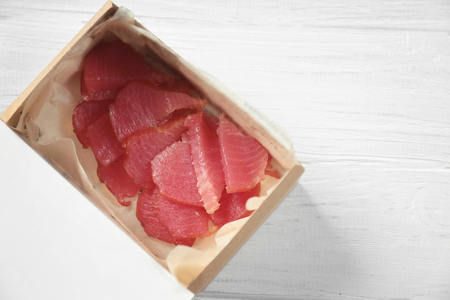 Cardboard box with delicious tuna on wooden tableの写真素材