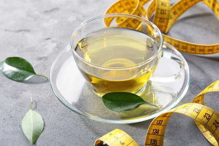 Cup of tea and measuring tape on table. Weight loss conceptの写真素材