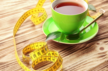 Cup of tea and measuring tape on wooden table. Weight loss conceptの写真素材