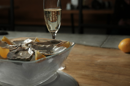 Delicious oysters with slices of lemon on ice cubes in bowlの写真素材