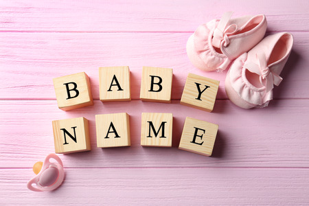 Wooden cubes with text BABY NAME, pacifier and booties on color backgroundの写真素材